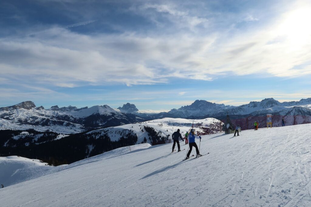 Folk der står på ski i Folgarida, Italien med udsigt over snebelagte bjerge.